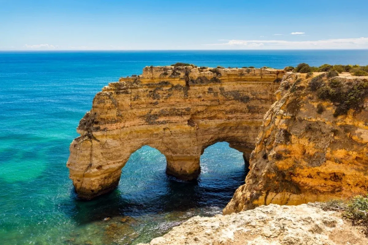 Golden limestone sea arches above turquoise water in the Algarve, Portugal