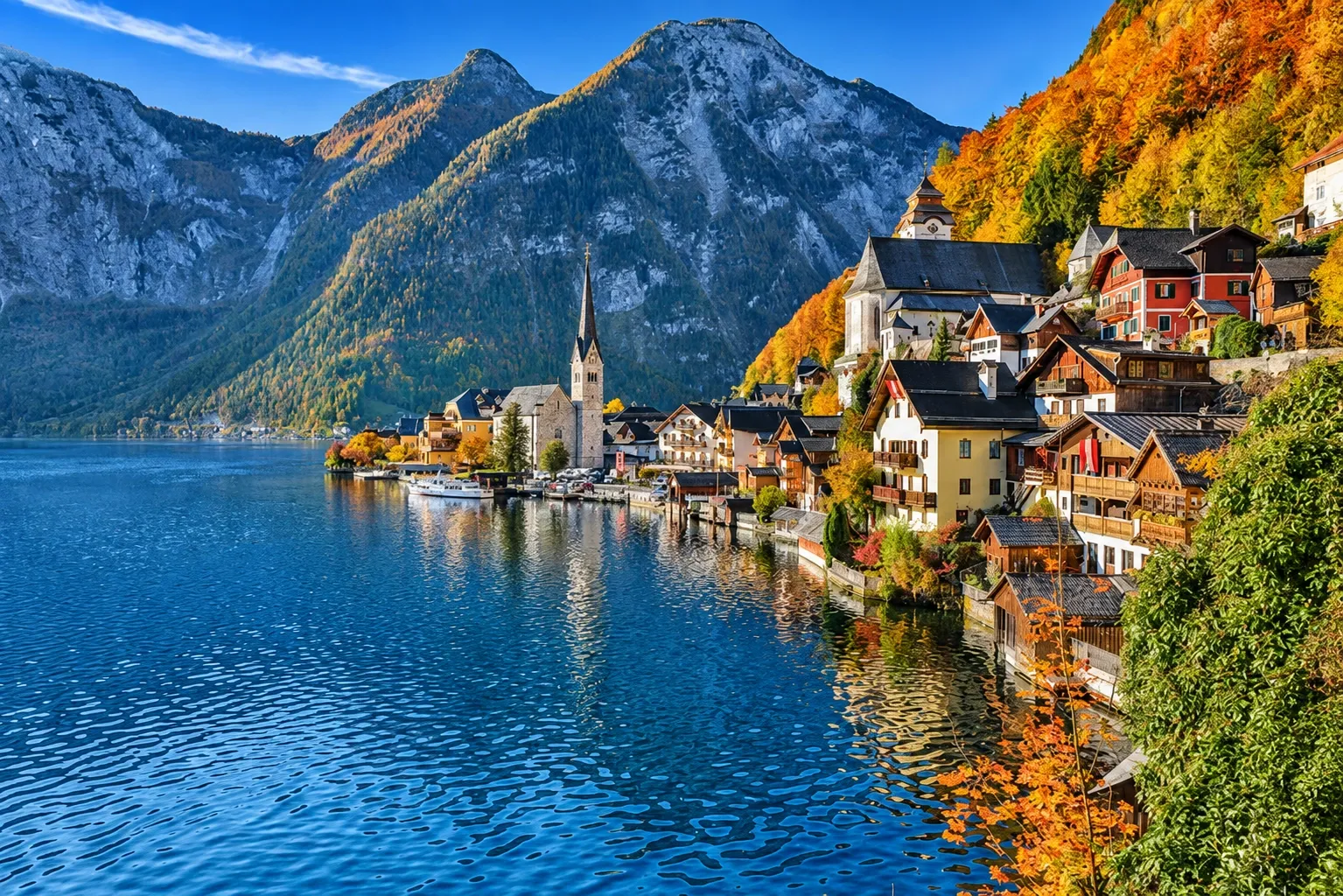the iconic postcard view of Hallstatt, a historic alpine village nestled along the pristine waters of the Hallstätter See (Lake Hallstatt) in the Salzkammergut region of Austria.