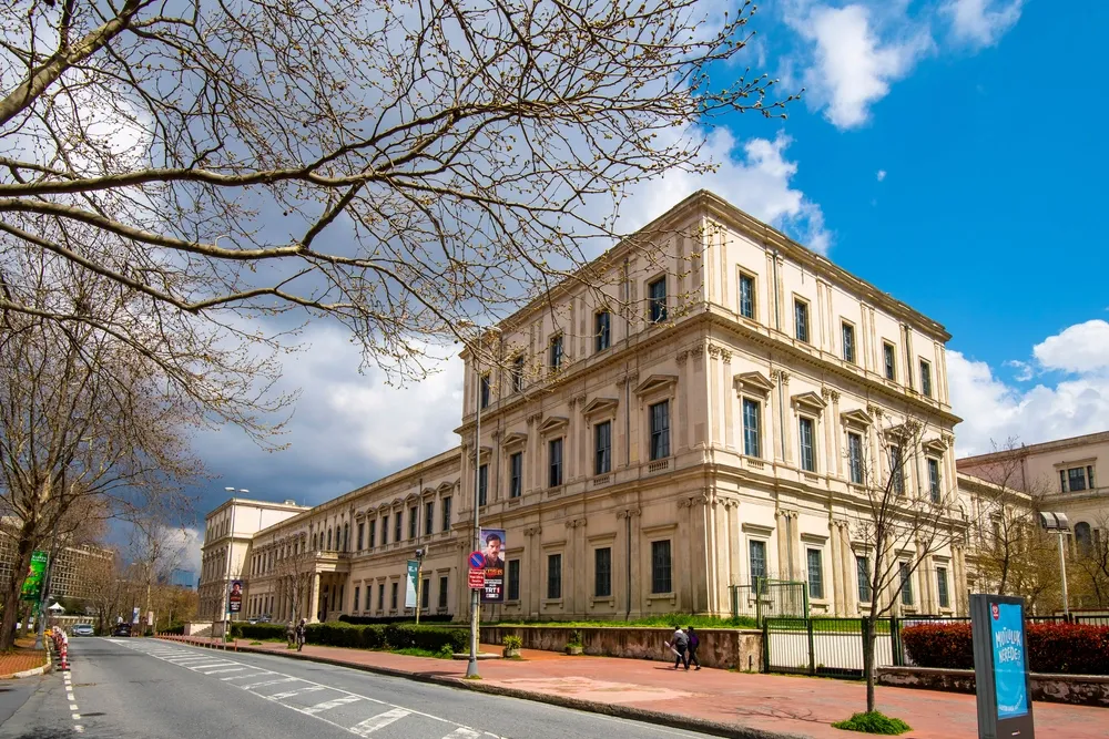 Istanbul Technical University building with a light stone façade, tree-lined street and bright blue sky in Turkey.