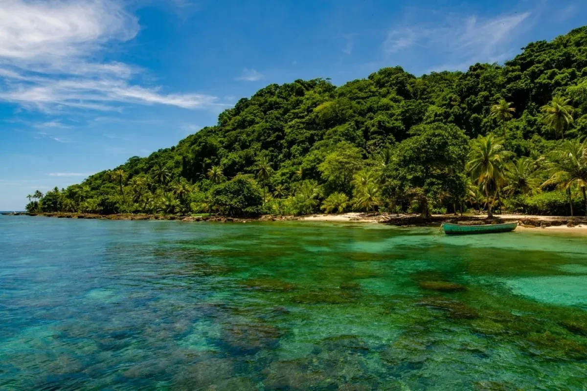 Small boat in a calm turquoise bay beside a forested tropical coast in Panama