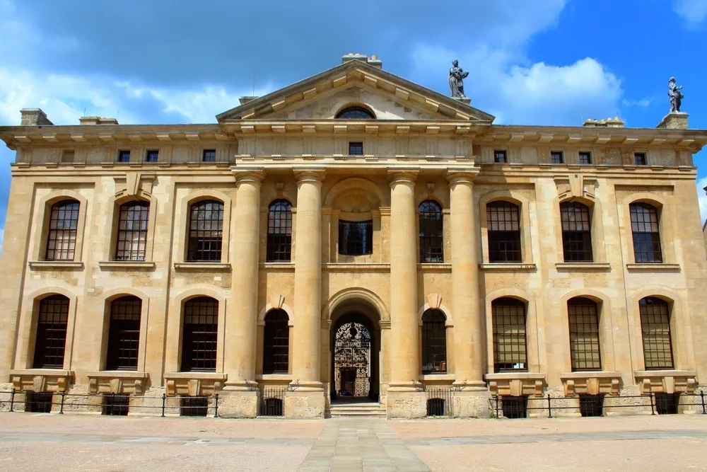 Historic University of Oxford building with classical stone columns, arched windows and a grand central entrance.